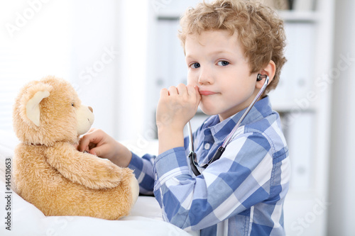 Child  patient afrer health exam playing as a doctor with stethoscope and teddy bear. photo