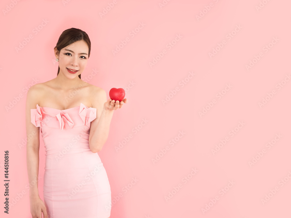 beautiful woman holding mini heart on hand,fashion girl on pink background beautiful woman holding mini heart on hand,fashion girl on pink background