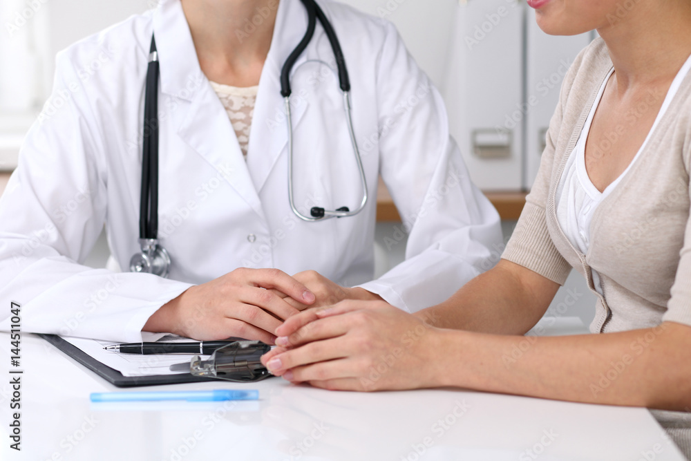 Close up of doctor and patient sitting at the desk while physician pointing into medical form hystory. Medicine and health care concept Close up of doctor and patient sitting at the desk while physician pointing into medical form hystory. Medicine and health care concept