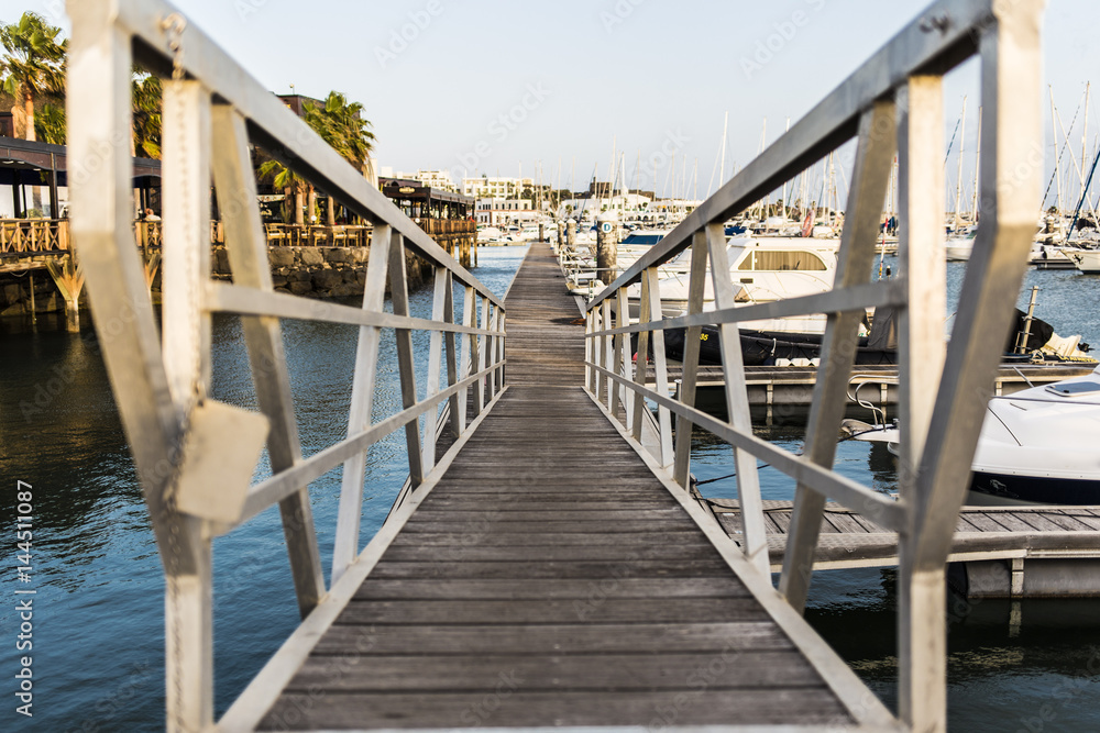 Chrome railing perspective on a thin pier sailing harbour