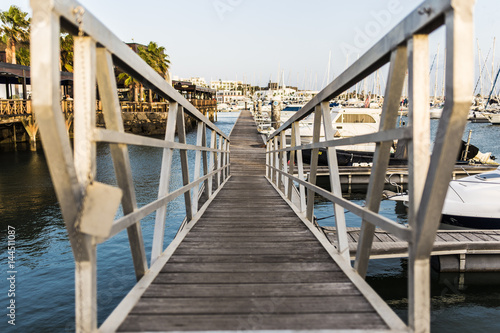 Chrome railing perspective on a thin pier sailing harbour © jordieasy