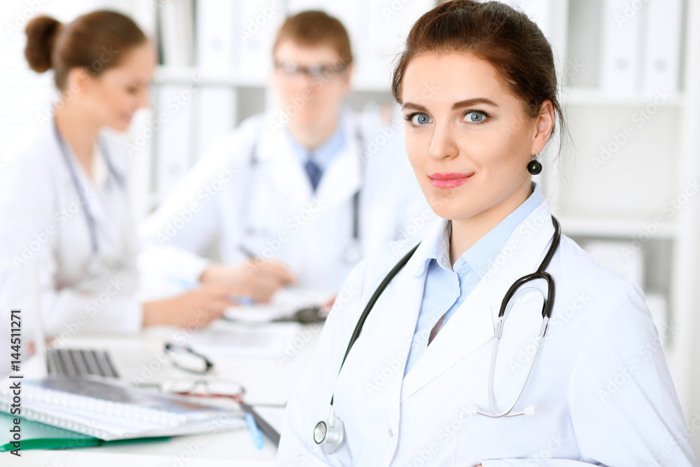 Happy doctor woman with medical staff at the hospital sitting at the table and discussing medical history Happy doctor woman with medical staff at the hospital sitting at the table and discussing medical history