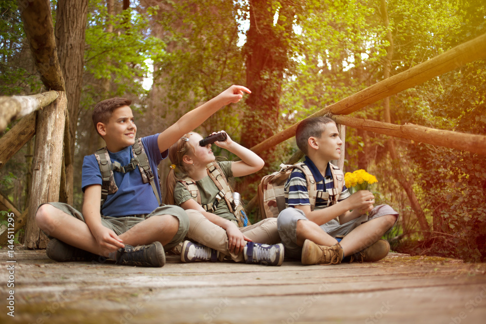 Young scouts sitting on old wooden bridge in the woods