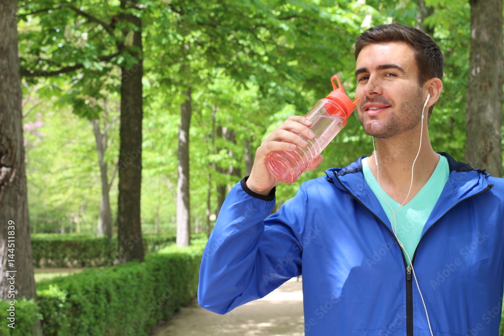 Healthy man drinking water after working out in the park with copy space Healthy man drinking water after working out in the park with copy space