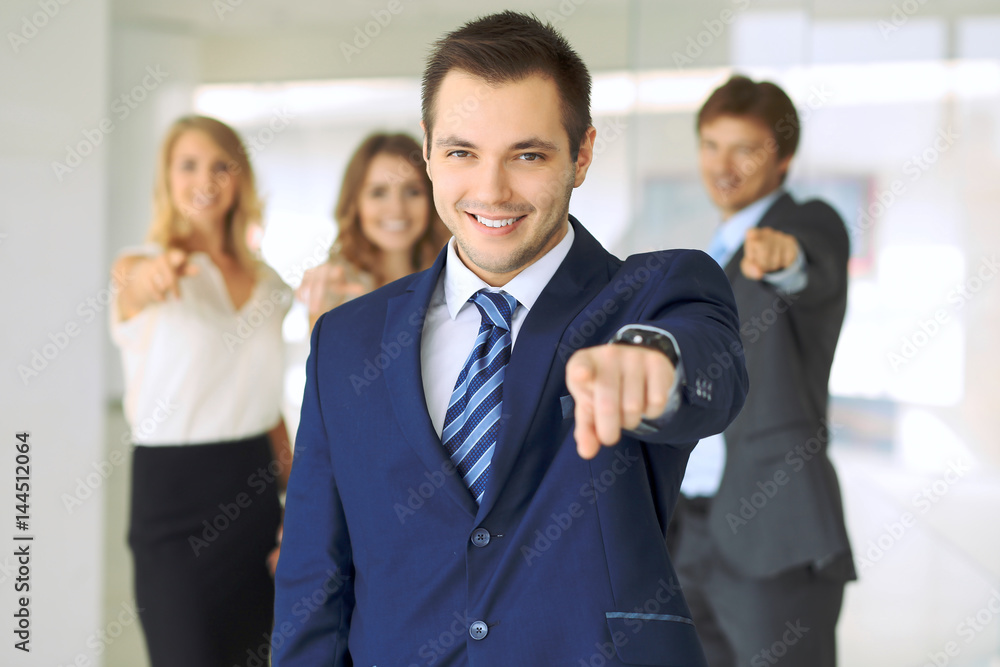 Happy smiling businessman and his colleagues pointing by finger into the camera. Concept of employer and success team. Happy smiling businessman and his colleagues pointing by finger into the camera. Concept of employer and success team.