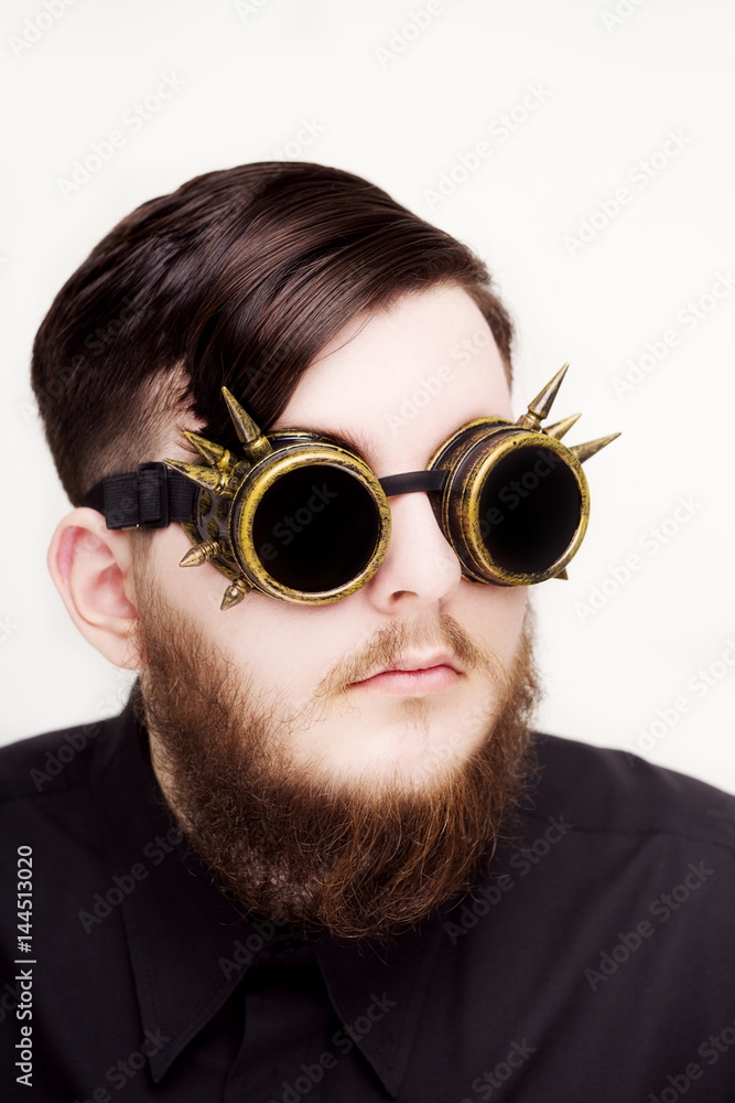 Handsome young man with long beard and moustache on face in steampunk glasseses on white background Handsome young man with long beard and moustache on face in steampunk glasseses on white background