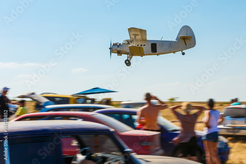 The old plane flies low over people and creates a futile situation at the air show.