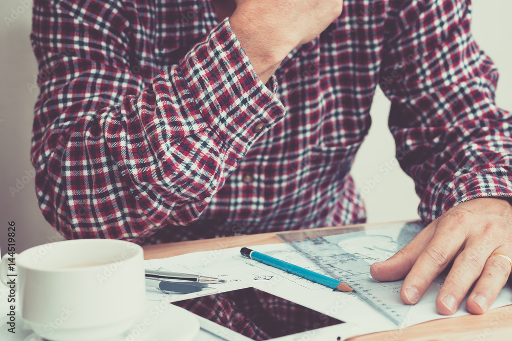 An engineer work for architectural project.With a cup of coffee,tools,drawing and white helmet on work table at home office. An engineer work for architectural project.With a cup of coffee,tools,drawing and white helmet on work table at home office.