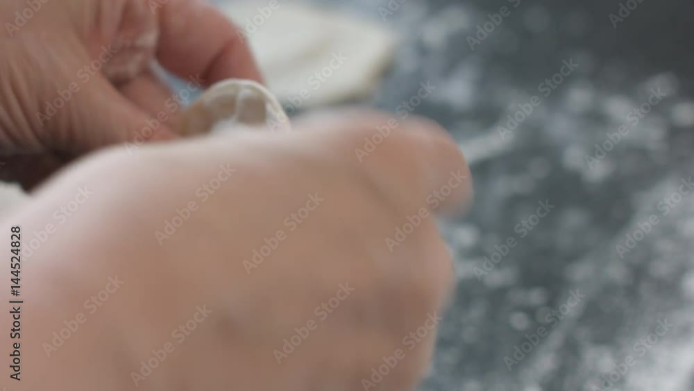 Close-up view of two woman's hands making meat dumplings. Close-up view of two woman's hands making meat dumplings.