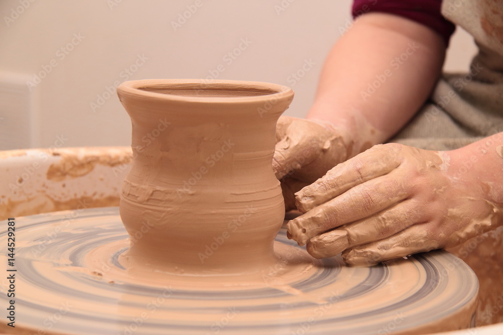 Hands of a potter, creating an earthen jar on pottery wheel. Hands of a potter, creating an earthen jar on pottery wheel.