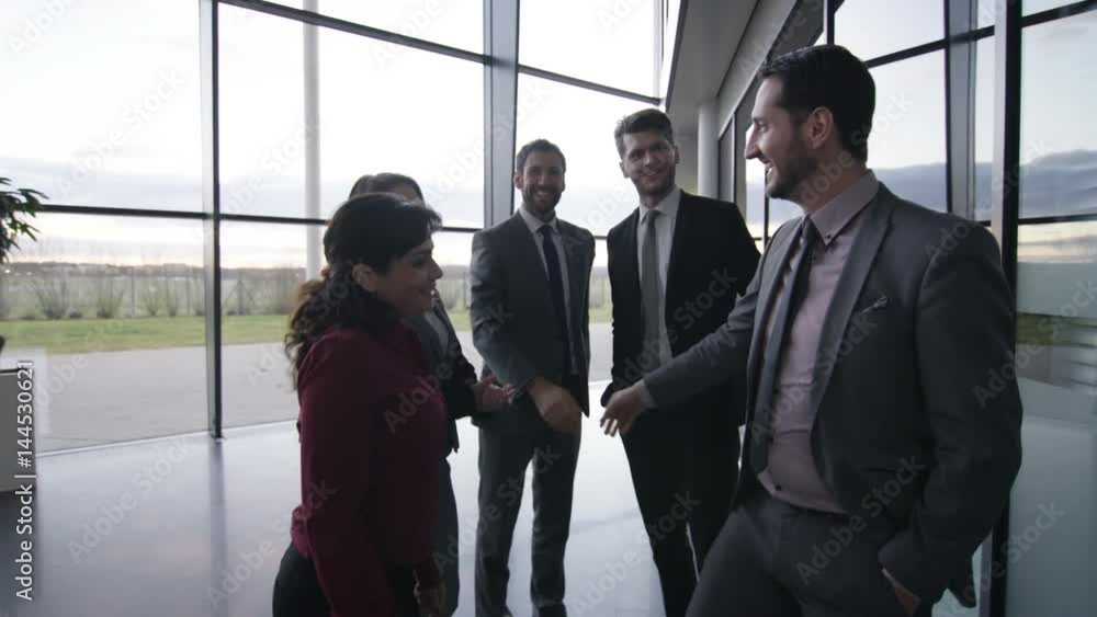 Business man & woman talking with colleagues & walking through modern office Business man & woman talking with colleagues & walking through modern office