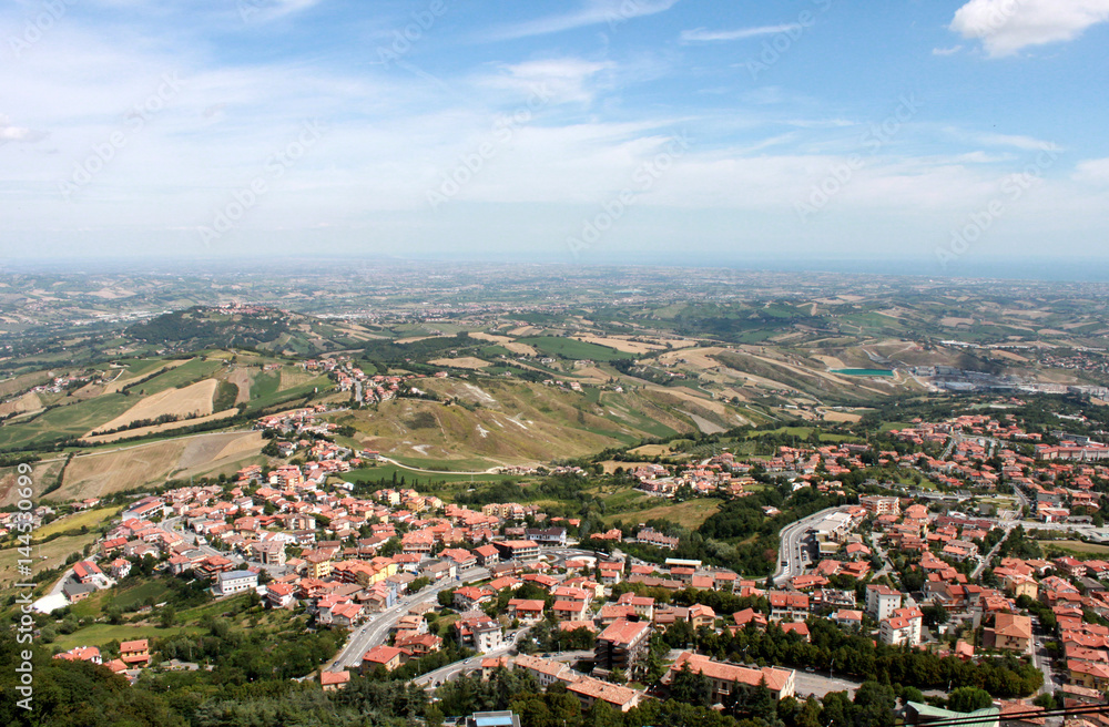 Obraz premium San Marino. Emilia-romagna. View on town with red roofs on blue sky background, horizontal view.