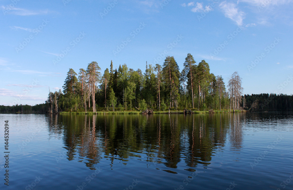 Russia, karelia. Island with forest on lake on blue sky background, horizontal view.