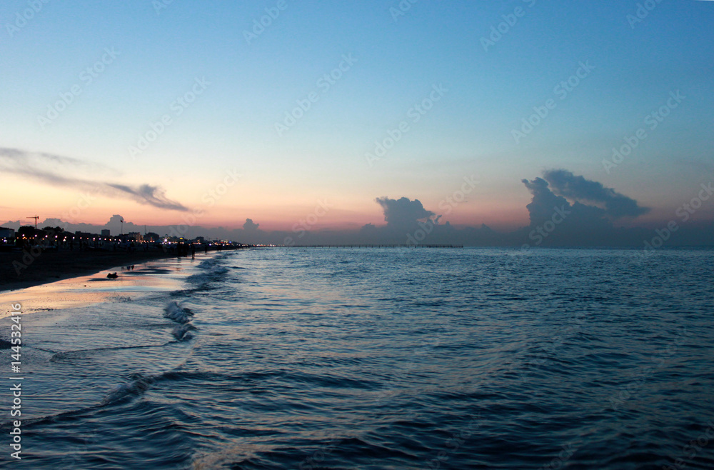 Fototapeta premium Italy. Emilia-Romagna. Rimini. Sunset on sea on blue pink sky background, horizontal view.