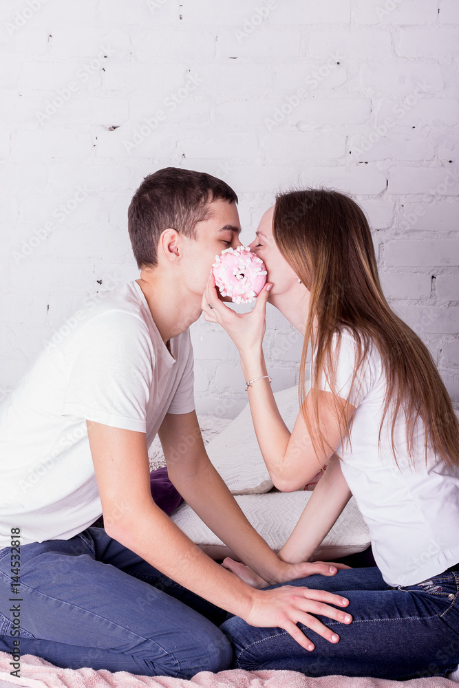 Couple sitting on the bed with a donut Couple sitting on the bed with a donut