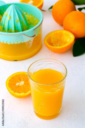 Freshly squeezed orange juice in turquoise juicer on white background