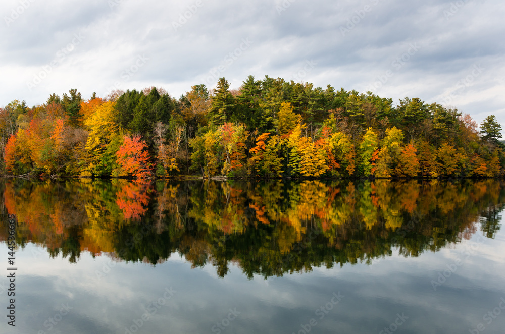 Wooded Island in a Mountain Lake and Reflection in Water. Beautiful Autumn Colours and Cloudy Sky.