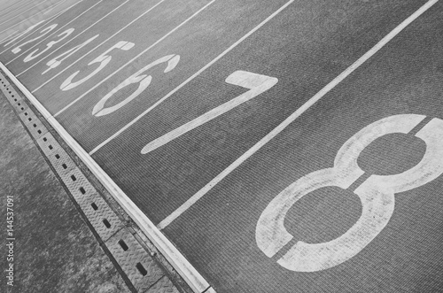 Running track with numbers from 1 to 8. Shot in a unique angle. A gutter along the track. Black and white image.