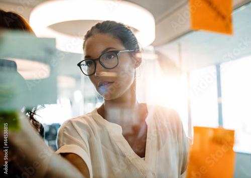 Asian businesswoman looking over a post it note wall and brainst photo