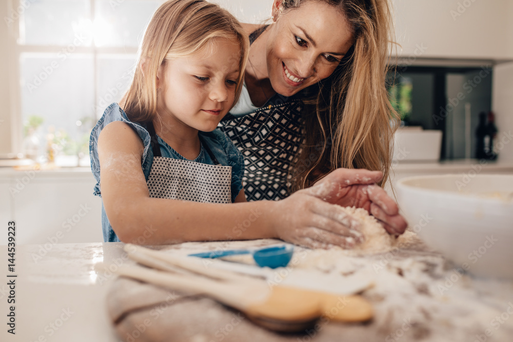 Mother teaching her daughter to make dough Mother teaching her daughter to make dough