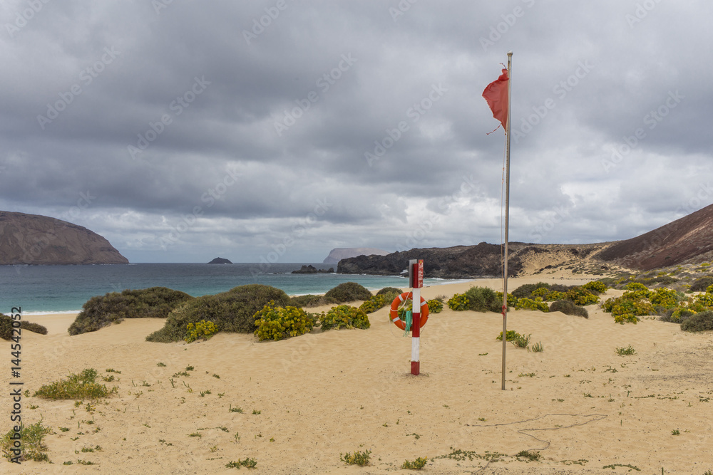 Red flag on a windy stormy beach Red flag on a windy stormy beach