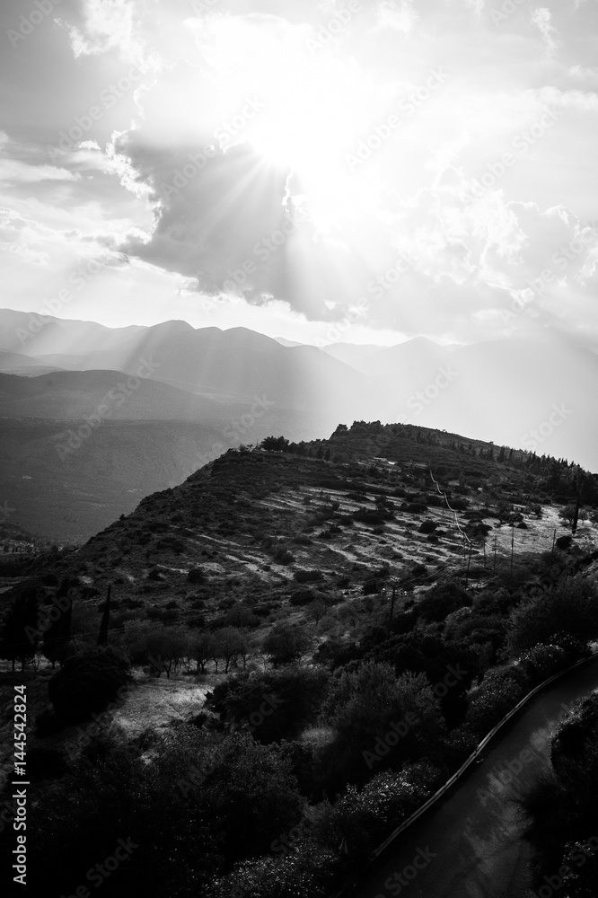 Greece, Delphi, August 2016, beautiful sun shining through the clouds lightning just part of hill. Panorama from one of city restaurants