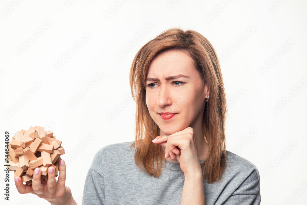 Attractive 24 year old business woman looking confused with wooden puzzle. Attractive 24 year old business woman looking confused with wooden puzzle.