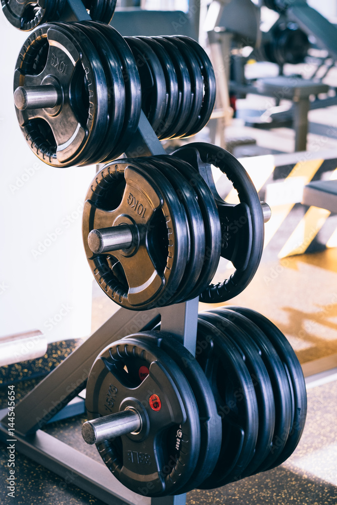 Set of metal barbells disks on barbbell holder in the fitness gym Set of metal barbells disks on barbbell holder in the fitness gym