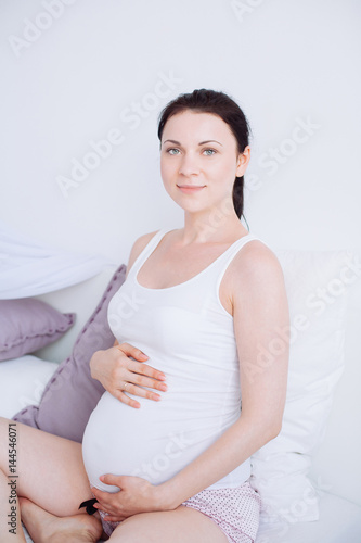 Young pregnant woman is sitting in the bedroom Free Download Young pregnant woman is sitting in the bedroom - GFXLoad