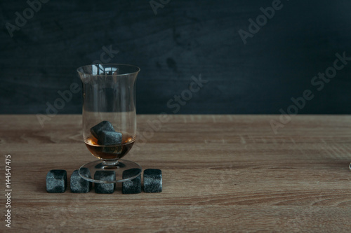 Stones for cooling whiskey and glases tulup on dark wooden background photo