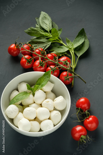 Mozzarella cheese, basil and tomatoes cherry on a gray background