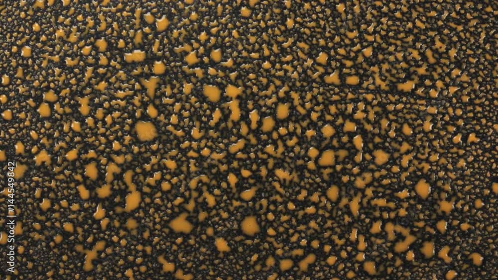 Falling drops of of yellow paint on a black surface. Falling drops of of yellow paint on a black surface.