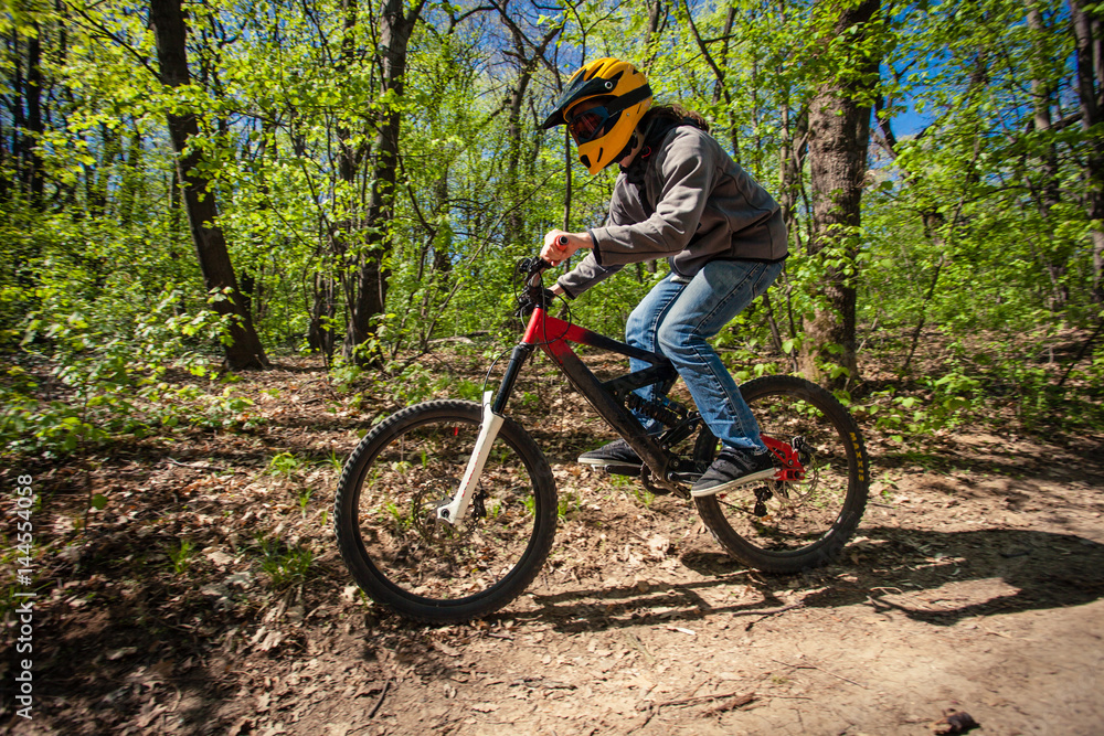 young man ride mountain bike through forest