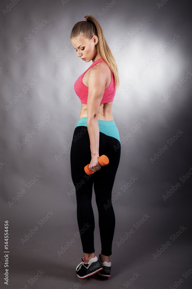 Young blonde involved in sports and fitness on a gray background Young blonde involved in sports and fitness on a gray background