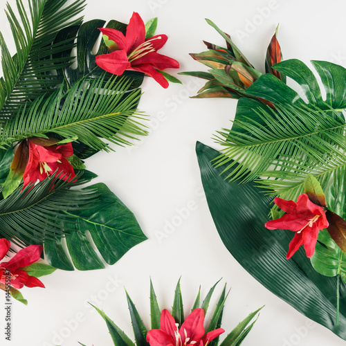 Creative layout made of tropical palm leaves and colorful flowers. Summer concept. Flat lay.