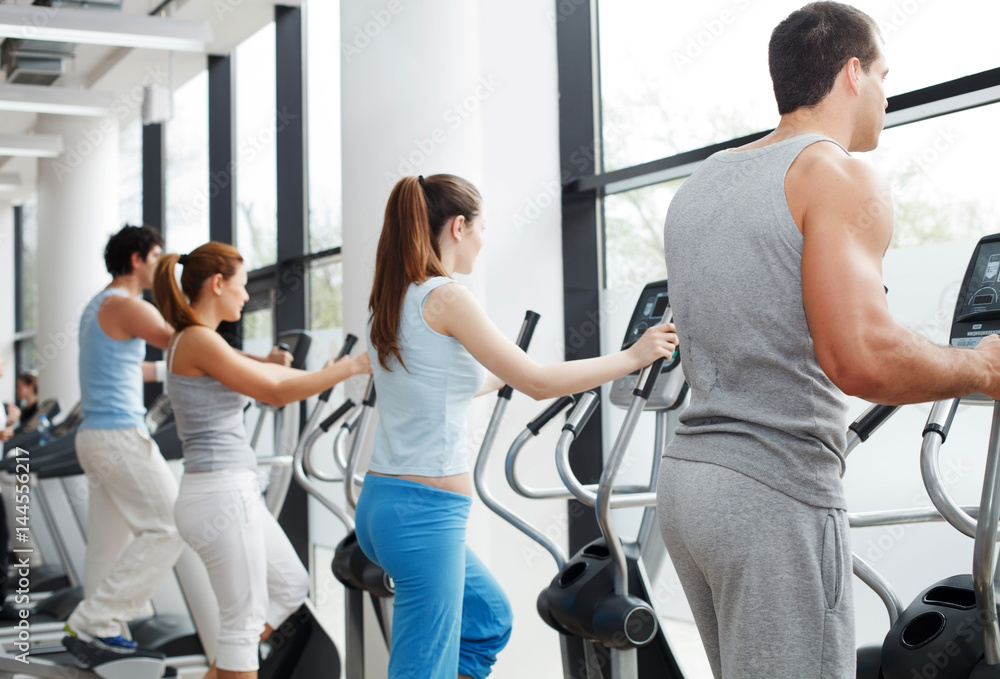 People exercising on cardio machines in the gym. People exercising on cardio machines in the gym.