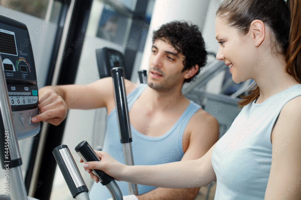 Fototapeta premium Trainer helping woman on exercise stepper machine.