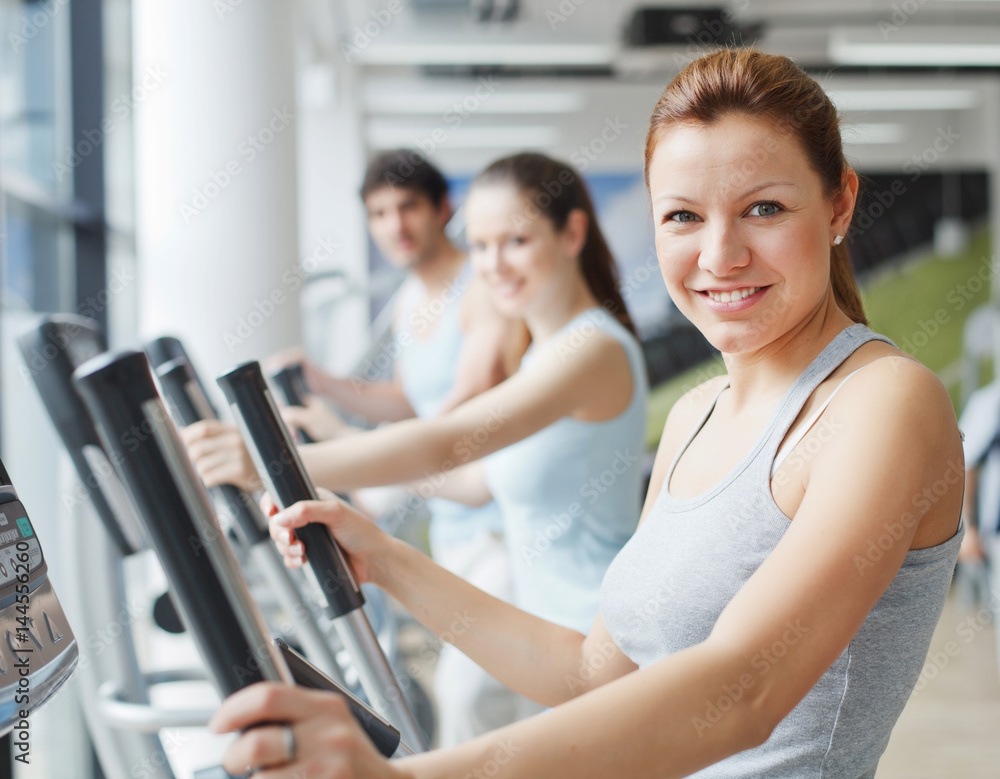 People exercising on cardio machines in the gym. People exercising on cardio machines in the gym.