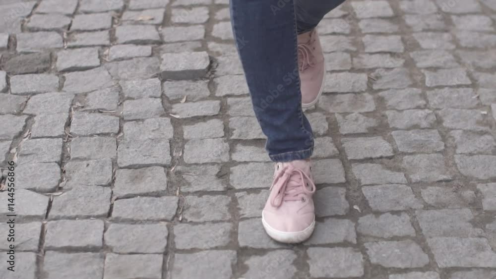 Girls feet in sneakers walking on the sidewalk Girls feet in sneakers walking on the sidewalk