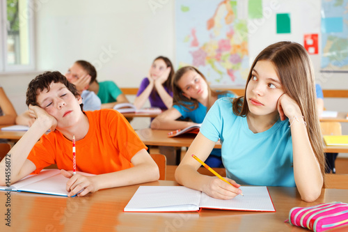 Schoolchildren bored in a classroom, during lesson.
