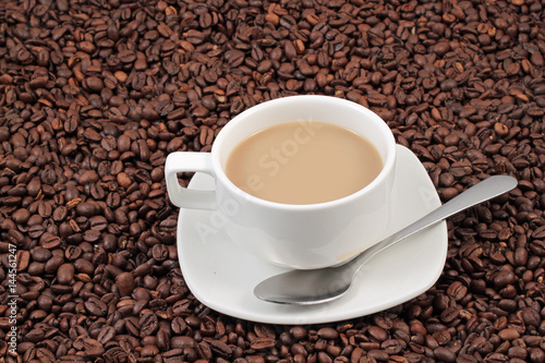 A white coffee cup on a background of whole coffee beans