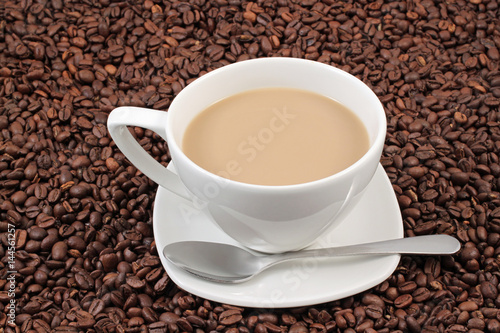 A white coffee cup on a background of whole coffee beans