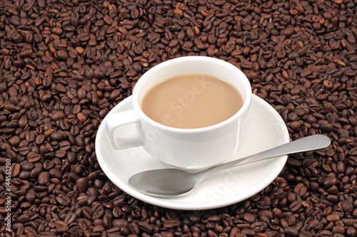 A white coffee cup on a background of whole coffee beans