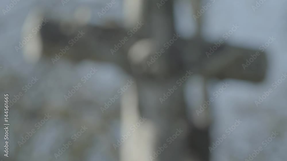 Old tombstone with Jesus cross on a sunny spring day. Defocus from cross. 4K in SLOG3. Medium shot. Old tombstone with Jesus cross on a sunny spring day. Defocus from cross. 4K in SLOG3. Medium shot.