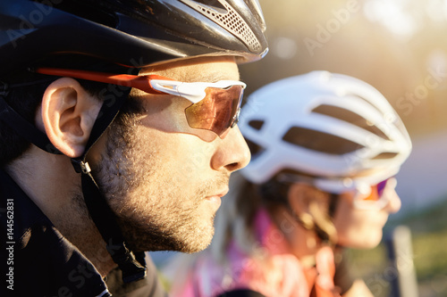 Headshot of young attractive bearded Caucasian man cyclist taking part in bicycle parade, selective focus on his head in helmet. Human and active leisure. Summer sports. Healthy lifestyle concept