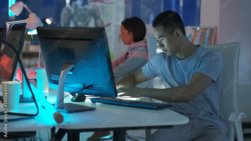 Young mixed ethnicity computer game design team working together in dark office Young mixed ethnicity computer game design team working together in dark office
