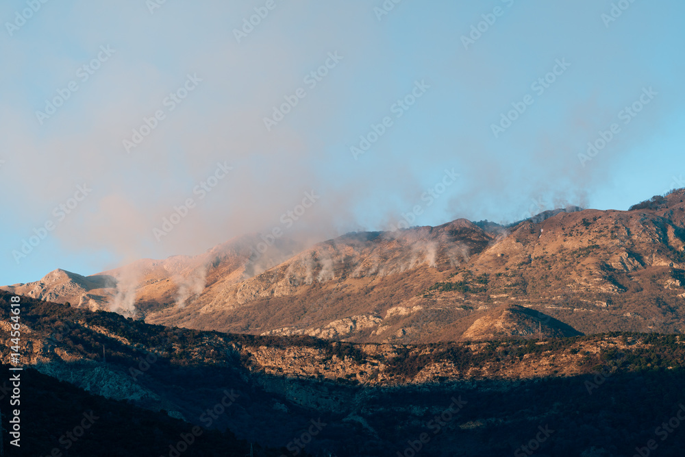 Fire in the mountains in the afternoon. Smoke over the mountains. Budva, Montenegro. Forest fires.