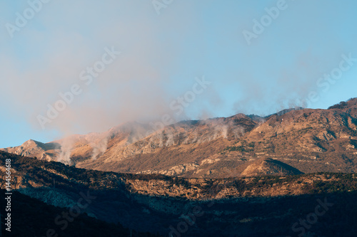 Fire in the mountains in the afternoon. Smoke over the mountains. Budva, Montenegro. Forest fires. © Nadtochiy