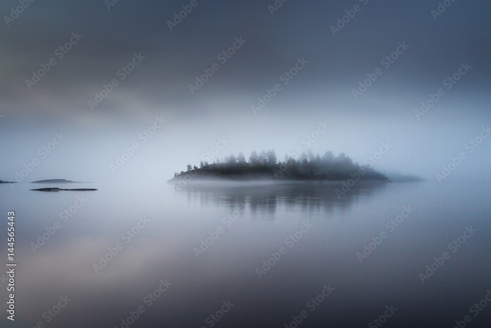 The island is in a fog. Karelia. Fog on the water.