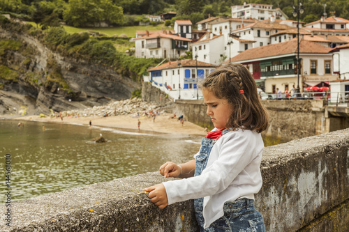 Fototapeta Naklejka Na Ścianę i Meble -  Girl watching seascape resting in the wall. Asturias. Spain